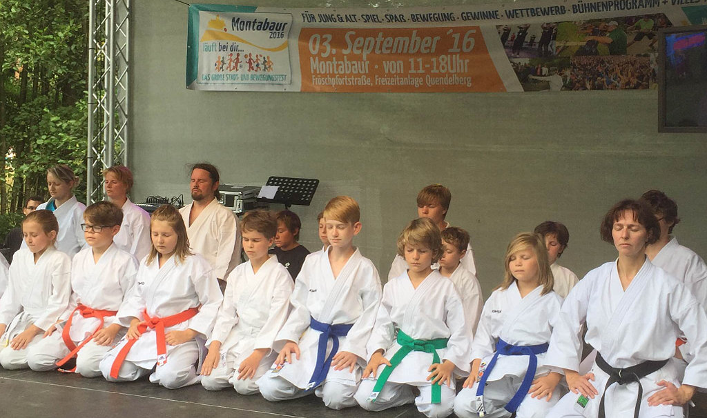 Karate-Gruppe im Kniesitz auf der Bühne